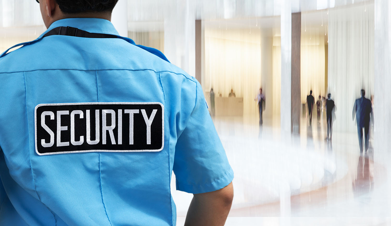 Uniformed security officer in a business office with a blurred background.